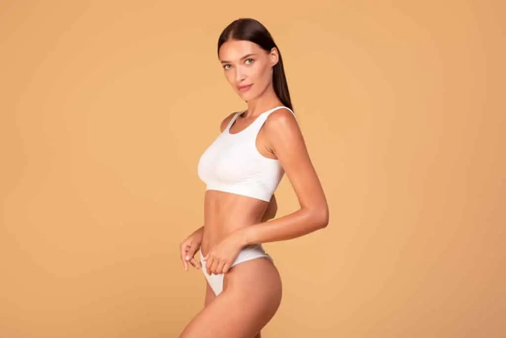 A woman confidently showcases her results after a body sculpting treatment
