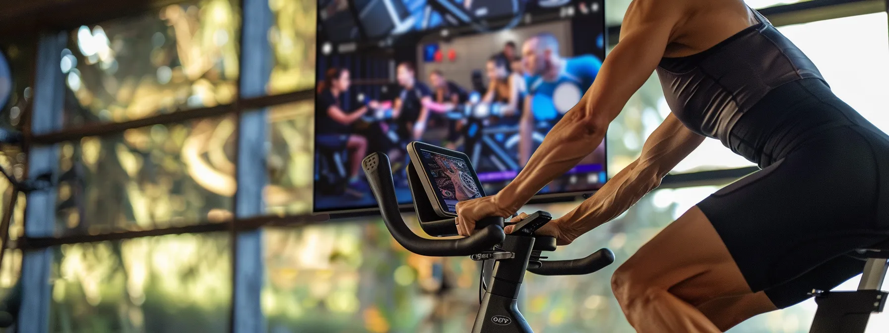 Person intensely cycling on a stationary bike with a screen displaying a virtual cycling class, emphasizing high-intensity indoor cycling for fitness and calorie burning.