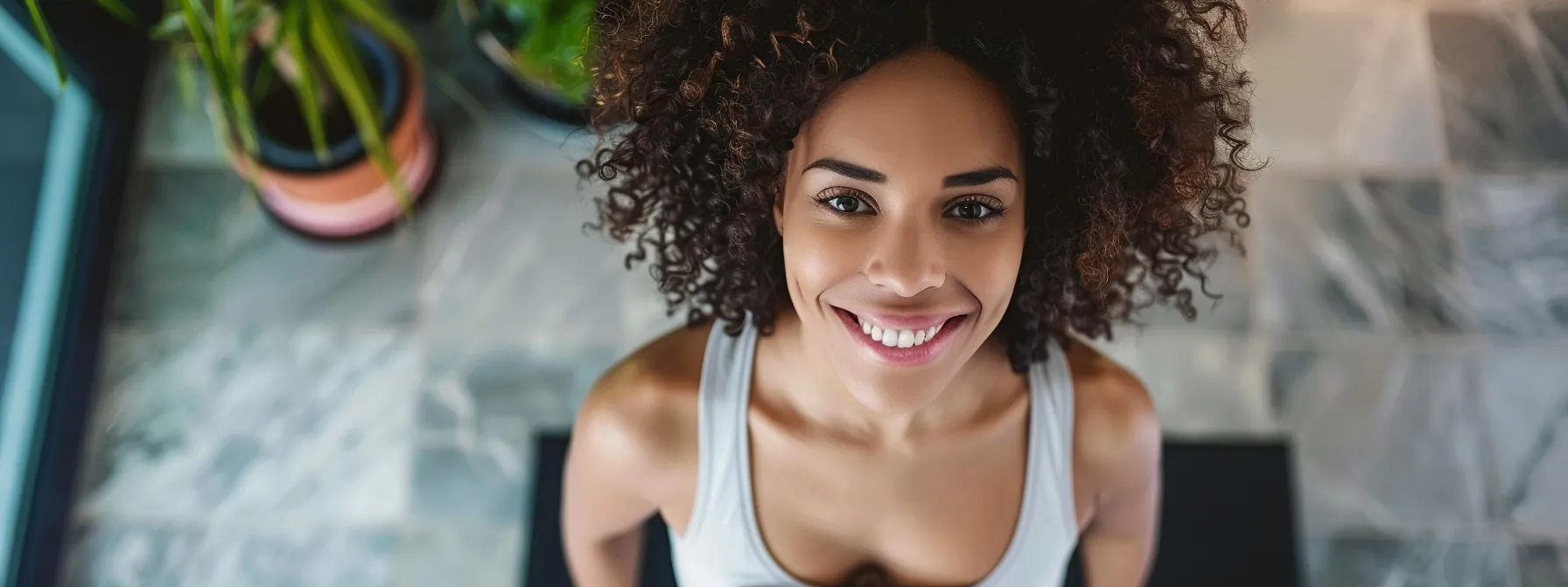 Smiling woman with curly hair in a fitness setting, embodying confidence and motivation for online weight loss journeys.